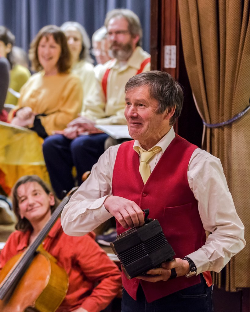 Man in red waistcoat playing a small accordian