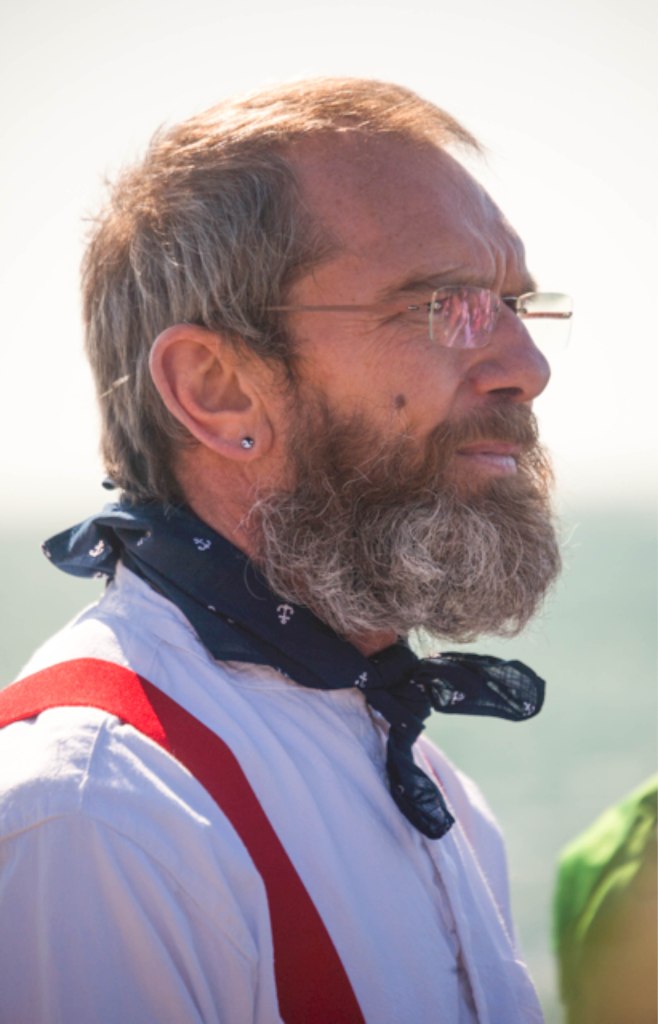 Man in open air, wearing white shirt, red braces and navey blue neckerchief
