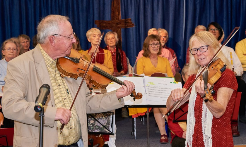 A man and a woman playing violins