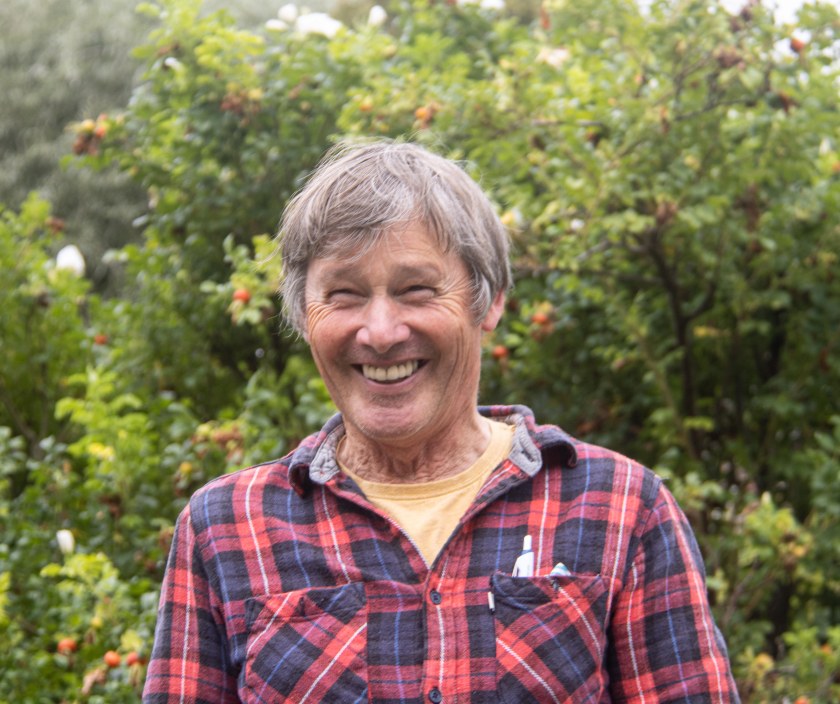 Man, smiling, against a hedge