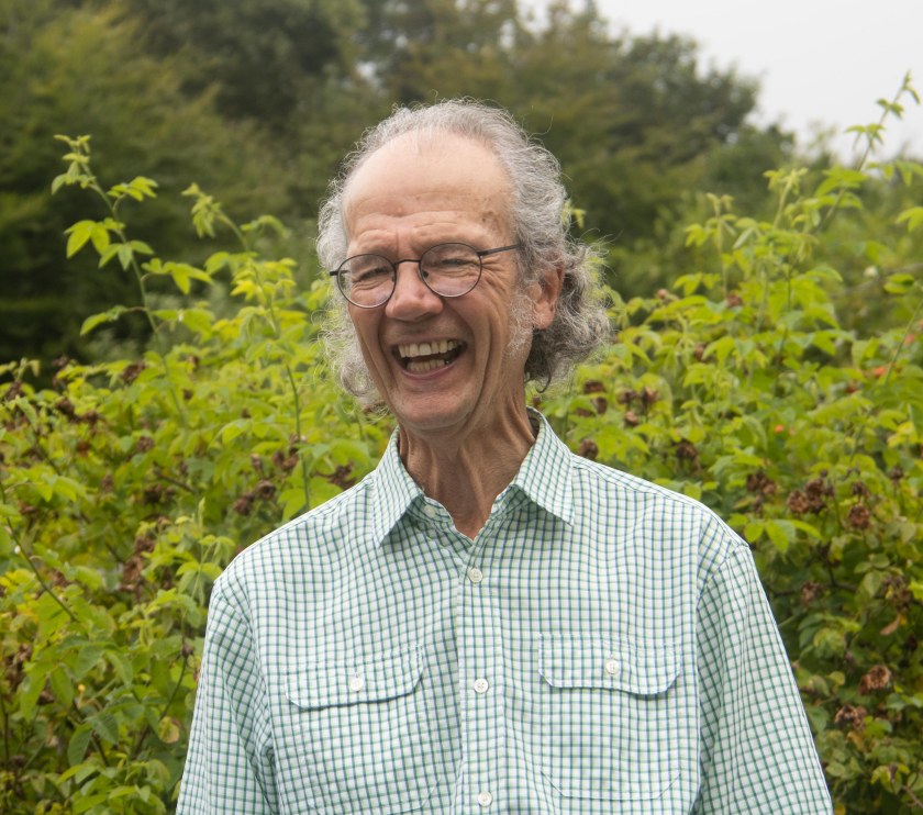 Man, smiling, against a hedge